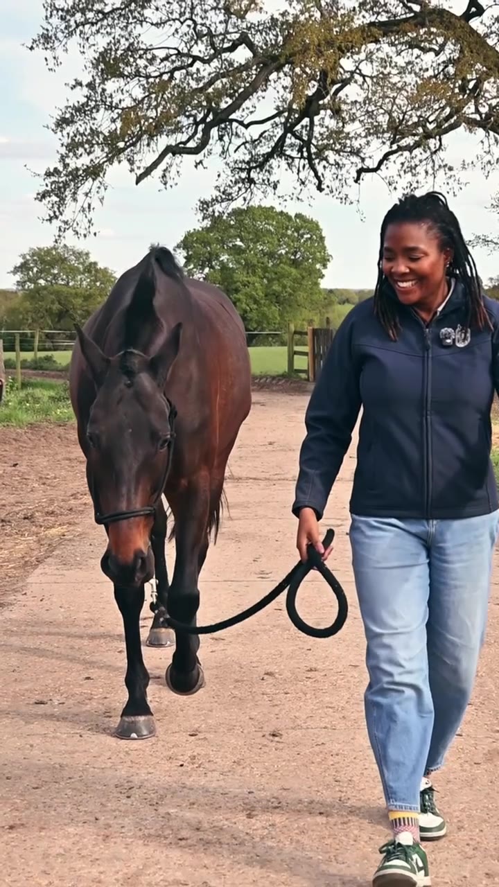 Zeze Oriaikhi-Sao walking beside a dark horse beneath trees at Champion Pride