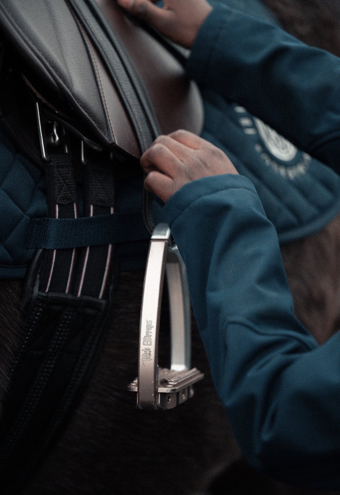 A Champion Pride operator adjusting a horse's girth and stirrup