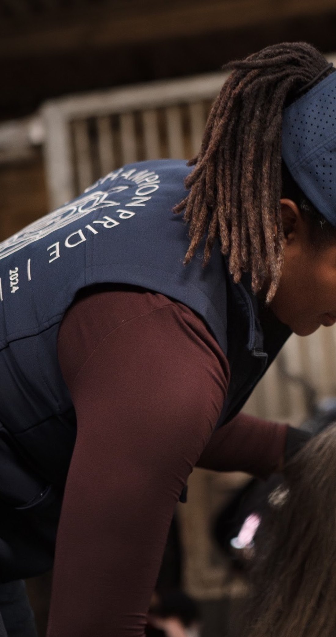 Champion Pride Operator grooming a horse in a navy gilet